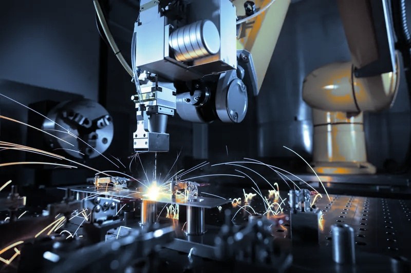 Robotic laser welding head joining metal parts with sparks