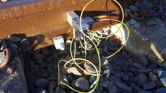 Fiber optic accelerometer clamped to the rail foot