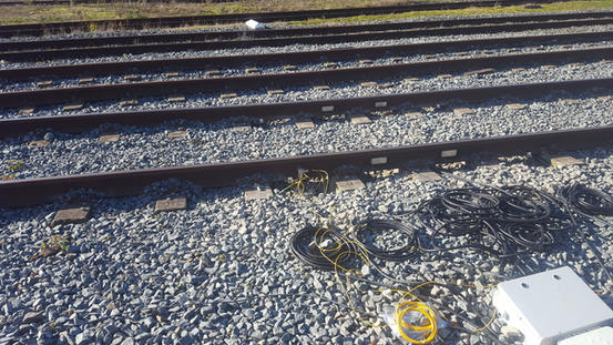 Fiber optic cables laid out alongside railway tracks during sensor installation
