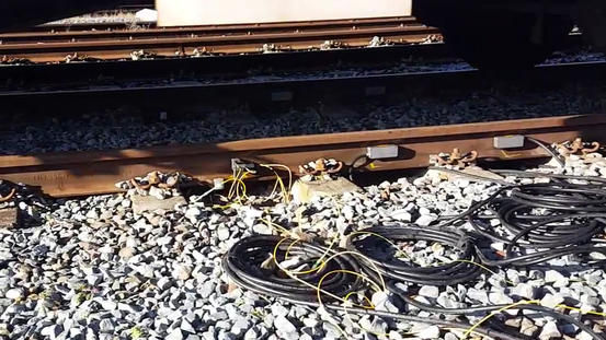 Sensors mounted on the rail with fiber cabling routed over the ballast