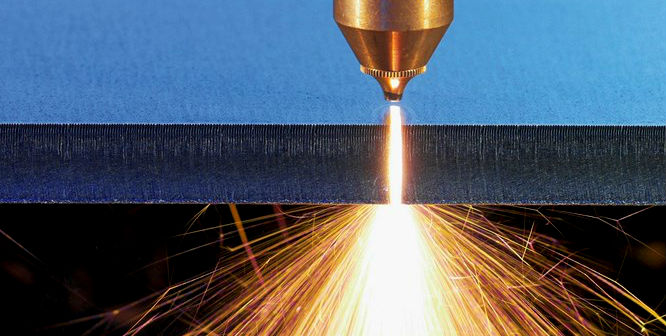 Fiber laser cutting nozzle cutting through a steel plate with sparks below